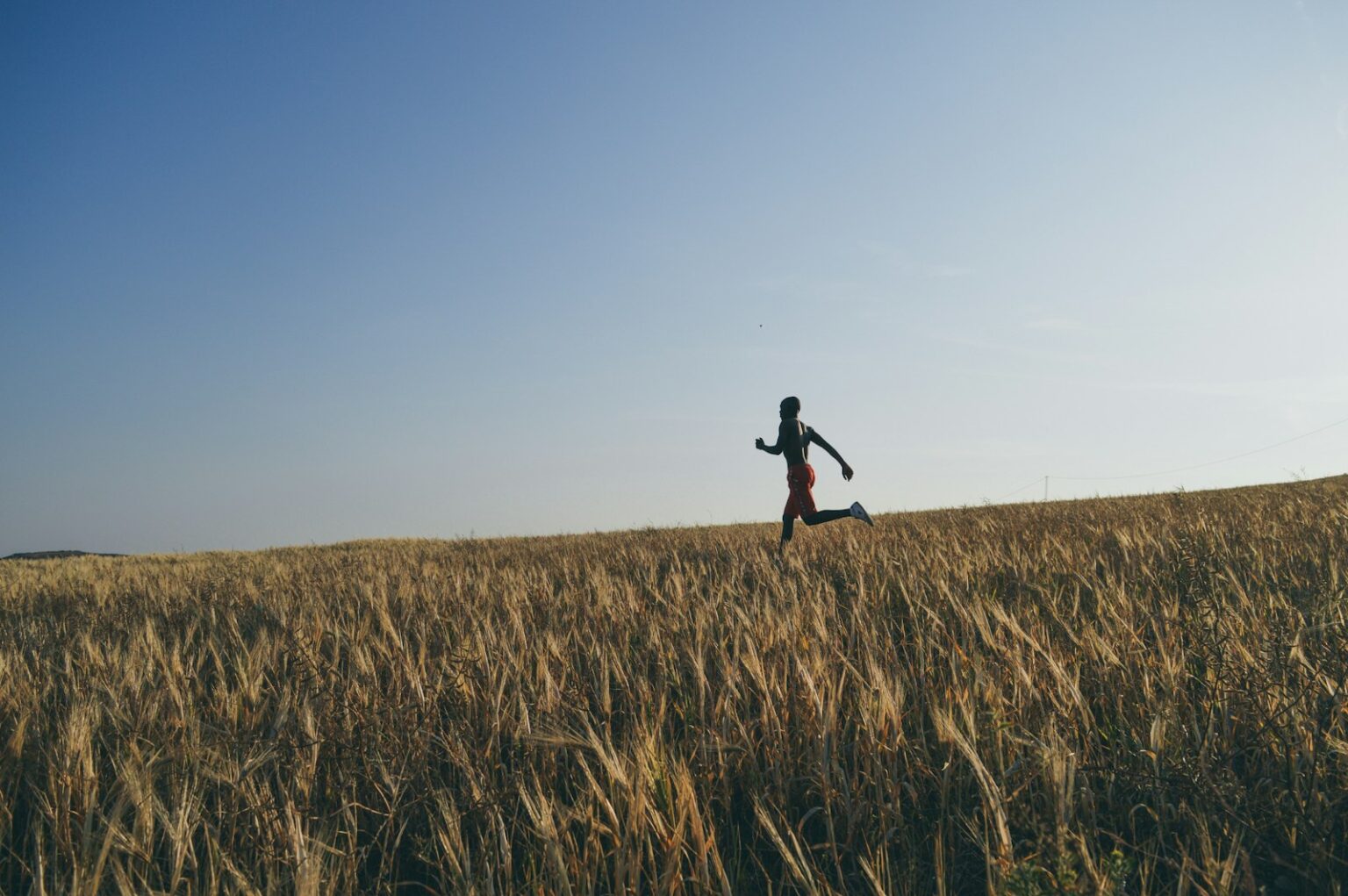 man in black jacket and black pants running on brown grass field during daytime
